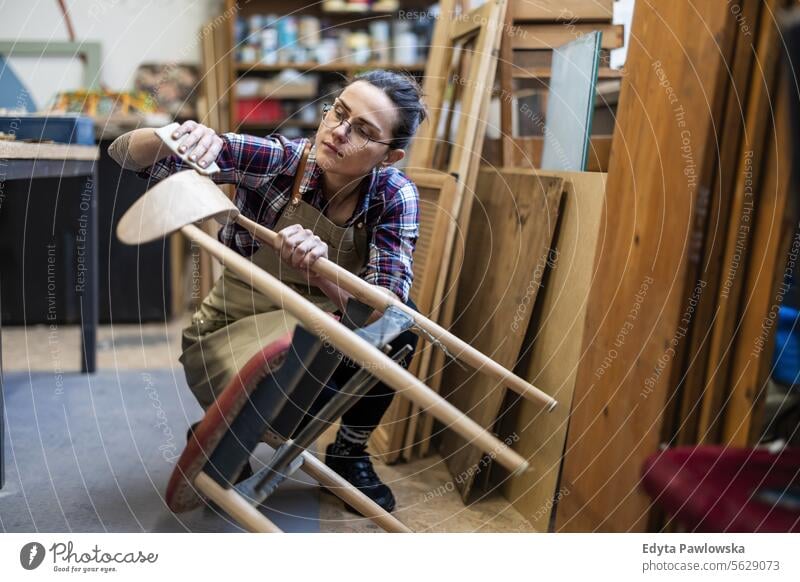 Schreinerin bei der Arbeit in ihrer Werkstatt Möbel Zimmerer wiederherstellend Schreinerei Holz Stuhl Gebäude Herstellung Handwerk Renovierung reparierend