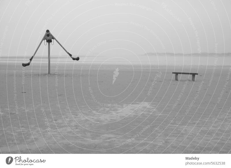 Verlassen Spielgeräte mit Bank bei Regen und Sturm am Strandspielplatz am Strand von St. Peter-Ording im Kreis Nordfriesland in Schleswig-Holstein im Herbst an der Nordseeküste in Schwarzweiß