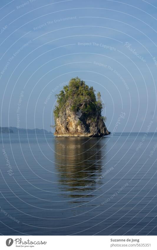 Idyllisches Bild einer vulkanischen Insel in Indonesien mit einer schönen Spiegelung im Meer. Die Stimmung des Bildes ist glücklich, ruhig und entspannt