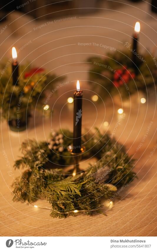 Weihnachten Blumenarrangement mit schwarz brennenden Kerze. Mittelstück festliche Dekoration mit Nadelbaumzweigen und roten Beeren. geblümt Ordnung Kerzen