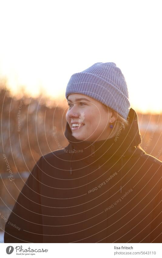 WEGSEHEN - SONNE GENIESSEN - WINTERZEIT Frau 18-30 Jahre Mütze Warmes Licht Winter Herbst Nasenring Junge Frau lachen hübsch Erwachsene Farbfoto Außenaufnahme