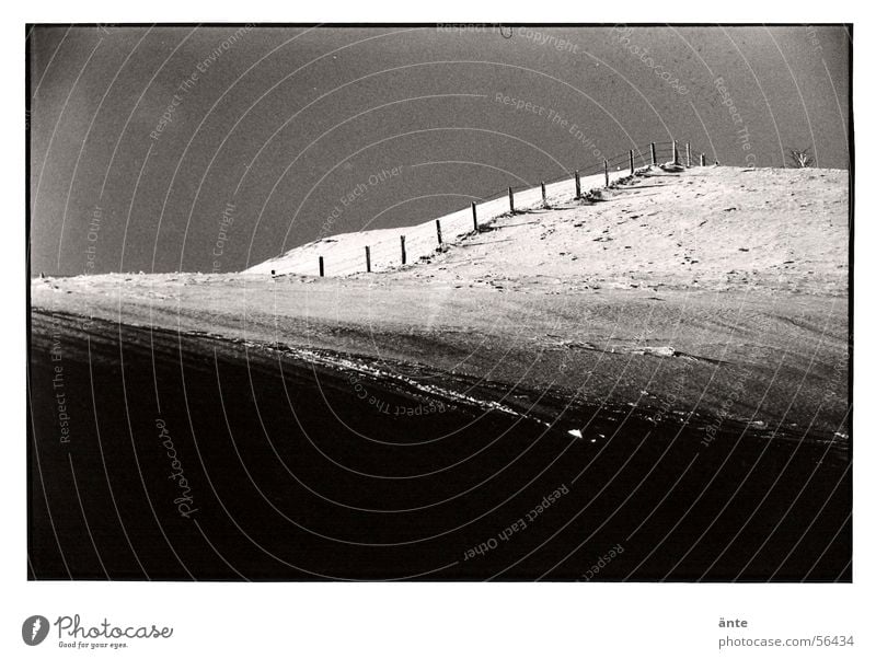 Zaun Winter kalt analog dunkel Hügel Vignettierung Fotolabor Schneelandschaft Ödland ruhig Einsamkeit Schwarzweißfoto Kontrast Landschaft Himmel Schatten