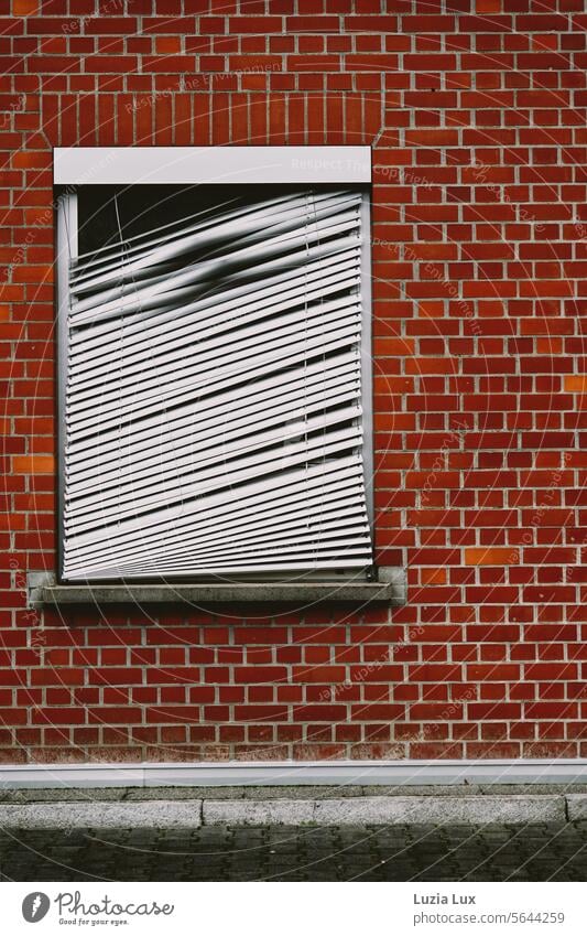 roter Backstein und ein Fenster mit kaputter Außenjalousie Backsteinwand Jalousie schief Leerstand Stadt urban Wand Fassade Mauer Backsteinfassade