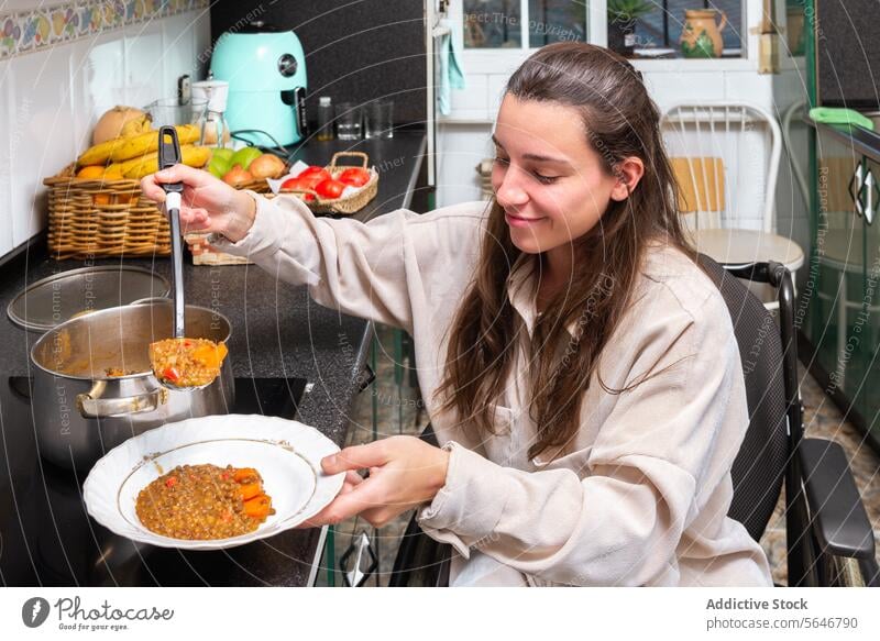 Unabhängiges Leben: Frau im Rollstuhl serviert Essen Mahlzeit Servieren Selbstständigkeit Küche Gesundheit Lächeln Selbstbedienung angepasst Lifestyle Ernährung