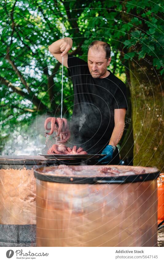 Fokussierter galizischer Koch beim Kochen von Oktopus im Topf galicisch Küchenchef Essen zubereiten Octopus Haken Dampftopf traditionell Methode Gastronomie