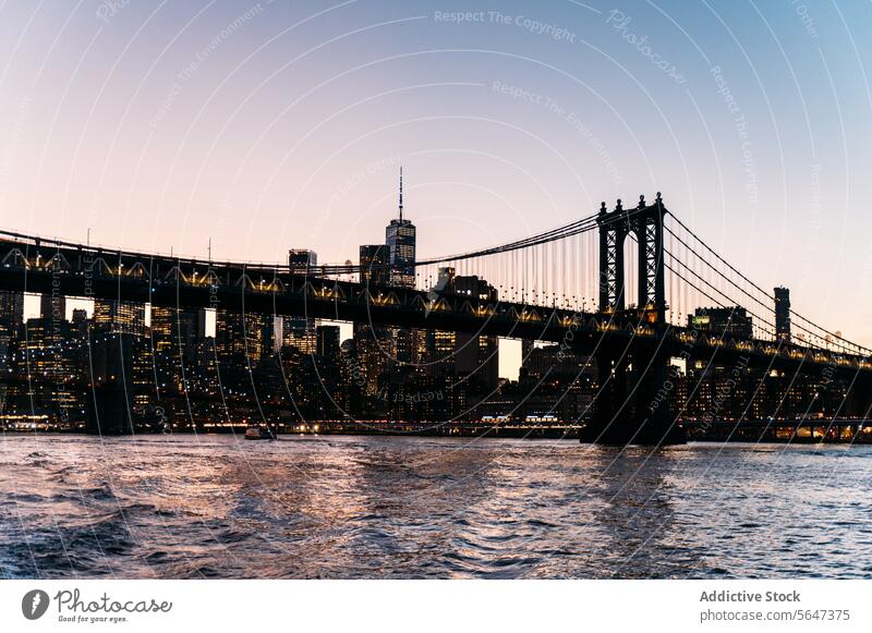 Beleuchtete Brücke über den Fluss in der abendlichen Stadt Suspension Wolkenkratzer Abend Großstadt Architektur leuchten Sonnenuntergang Stadtzentrum