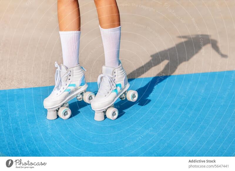 Crop-Frau in Quad-Rollschuhen Turnschuhe auf bunten Sportplatz Bein vierfach Rolle Schlittschuh Kniestrümpfe Sportpark trendy Stil Schatten aktiv Sportlerin