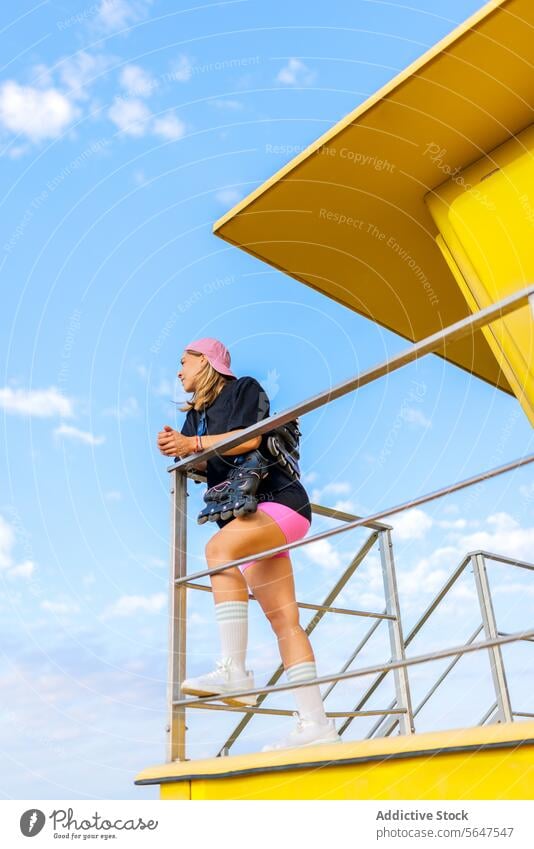 Weibliche Skaterin in voller Länge gegen blauen Himmel Frau Schlittschuh Rettungsschwimmer Hütte Strand Reling Lehnen niedriger Winkel inline Rolle Lifestyle