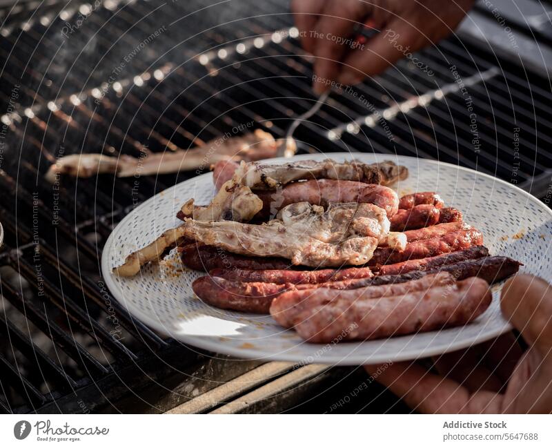 Crop-Koch bei der Zubereitung von Fleisch und Hotdogs auf der Grillmaschine vorbereiten Grillrost Maschine Küchenchef verwenden Gabel Barbecue Lebensmittel