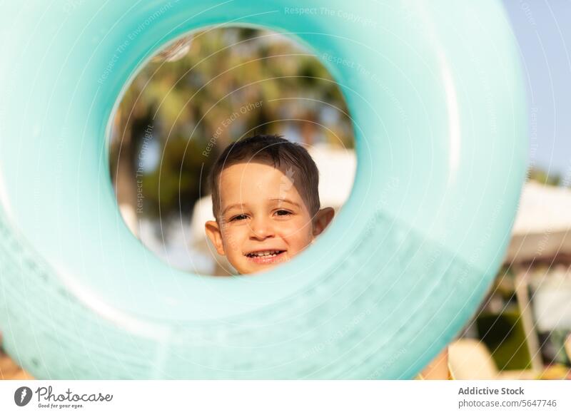 Junge spielt Guckguck mit Schwimmring am Strand Kind spielen Schwimmer Peekaboo sonnig Spaß im Freien Aktivität Spielzeit Sommer Urlaub Feiertag Freude Glück