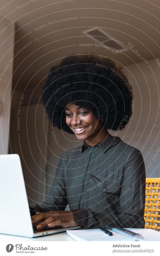 Fröhliche schwarze Frau tippt auf einem Laptop Arbeit Browsen online Tippen freiberuflich Arbeitsplatz abgelegen Internet modern Netbook Surfen heimwärts