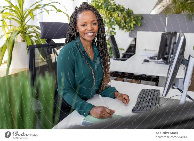 Glückliche Geschäftsfrau sitzt am Computer im Büro Porträt Schreibtisch selbstbewusst Lächeln Monitor Brille Arbeitsplatz Afro-Look Textfreiraum Unternehmer