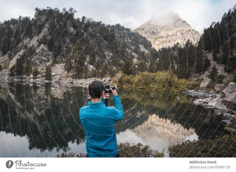 Anonymer Mann fotografiert majestätische Berge mit Kamera Tourist fotografieren Berge u. Gebirge Fotokamera See Abenteuer Landschaft Urlaub Fotograf Natur