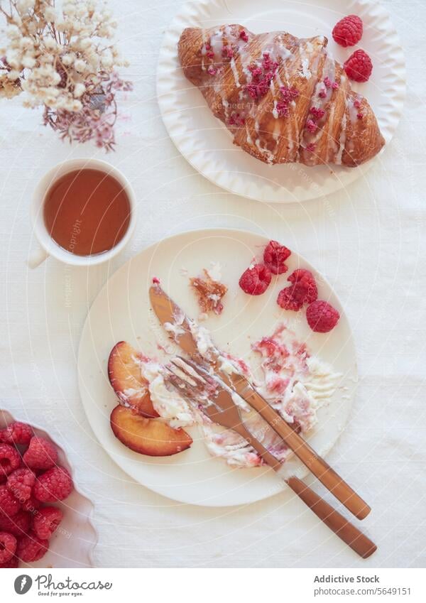 Leckeres Croissant mit Himbeere und Tee auf weißem Teller im Restaurant Himbeeren Frühstück Lebensmittel Dessert Besteck lecker dienen geschmackvoll Tisch