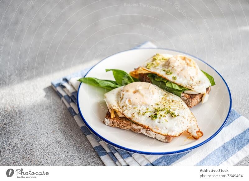 Leckeres Toastbrot mit Blattspinat, Spiegeleiern und Pestosauce zum Frühstück Ei Zuprosten Spinat gebraten dienen Saucen appetitlich Teller Serviette