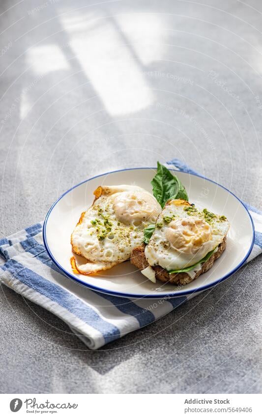 Leckeres Toastbrot mit Blattspinat, Spiegeleiern und Pestosauce zum Frühstück Ei Zuprosten Spinat gebraten dienen Saucen appetitlich Teller Serviette