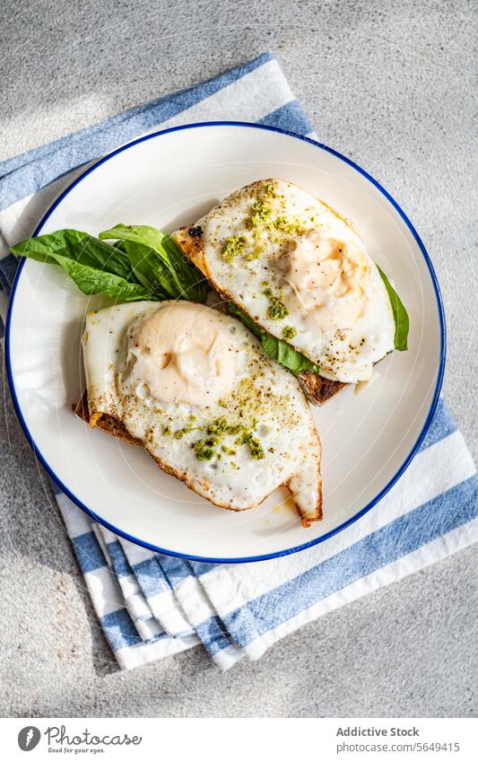 Leckeres Toastbrot mit Blattspinat, Spiegeleiern und Pestosauce zum Frühstück Ei Zuprosten Spinat gebraten dienen Saucen appetitlich Teller Serviette