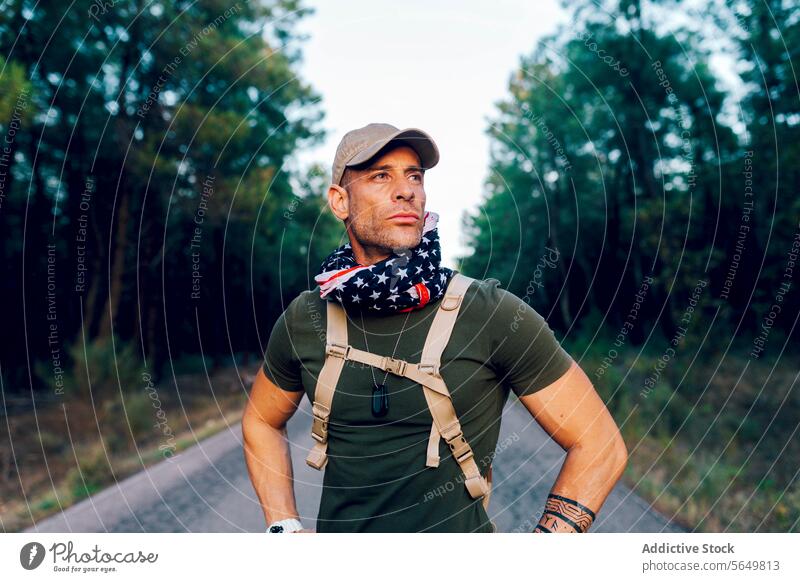 Männliches Kommando mit amerikanischer Flagge um den Hals gewickelt und mit Stolz wegschauend, während es auf der Straße steht Mann Soldat Militär Amerikaner