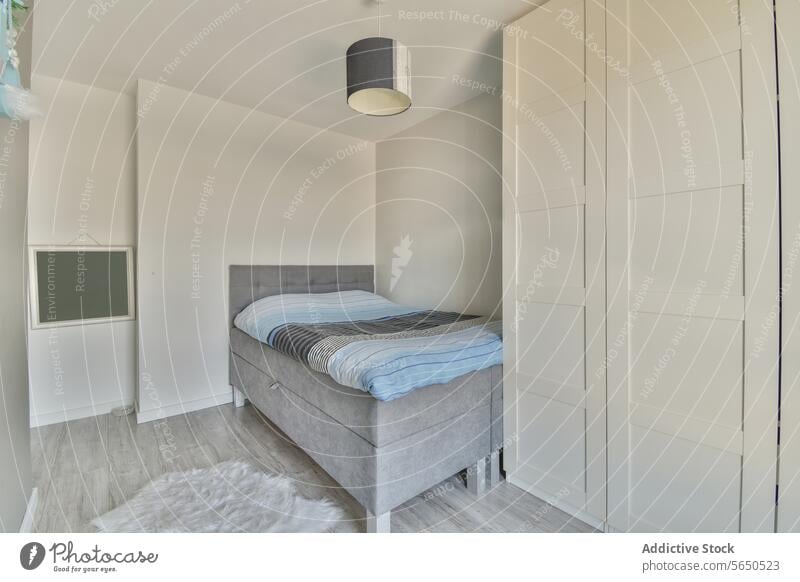 Schlafzimmer mit gemütlichem Bett und weißem Kleiderschrank bequem klein Appartement leer Möbel Stock Schmuckanhänger Licht Wand Textfreiraum Streu Bettwäsche