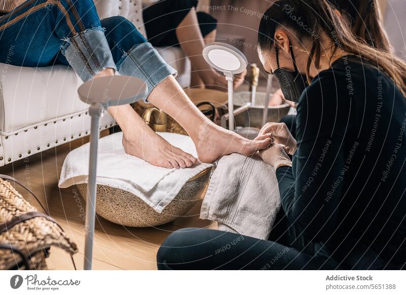 Crop Kosmetikerin tun Pediküre an Kunden im Salon mit Nagelfeile zu geben Form Klient Aktenordner Schönheit Verfahren Leckerbissen nageln Dienst professionell