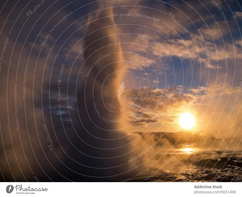 Majestätischer Geysirausbruch bei Sonnenuntergang mit aufsteigendem Dampf vor einem dramatischen Himmel in Island Eruption Verdunstung Natur Landschaft