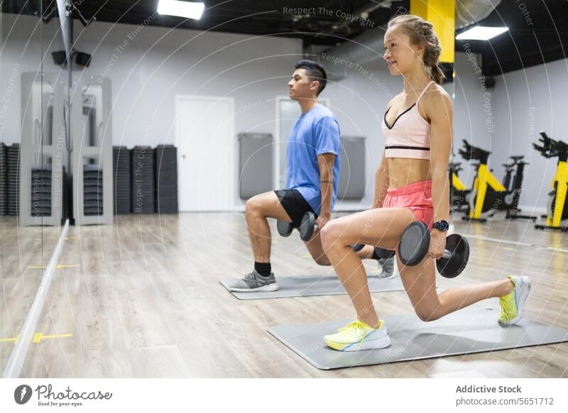 Fitness-Enthusiasten bei der Ausführung von Lunges im Fitnessstudio Training Übung Ausfallschritt Kurzhantel Gesundheit Fokus aktiv Lifestyle Stärke Ausdauer