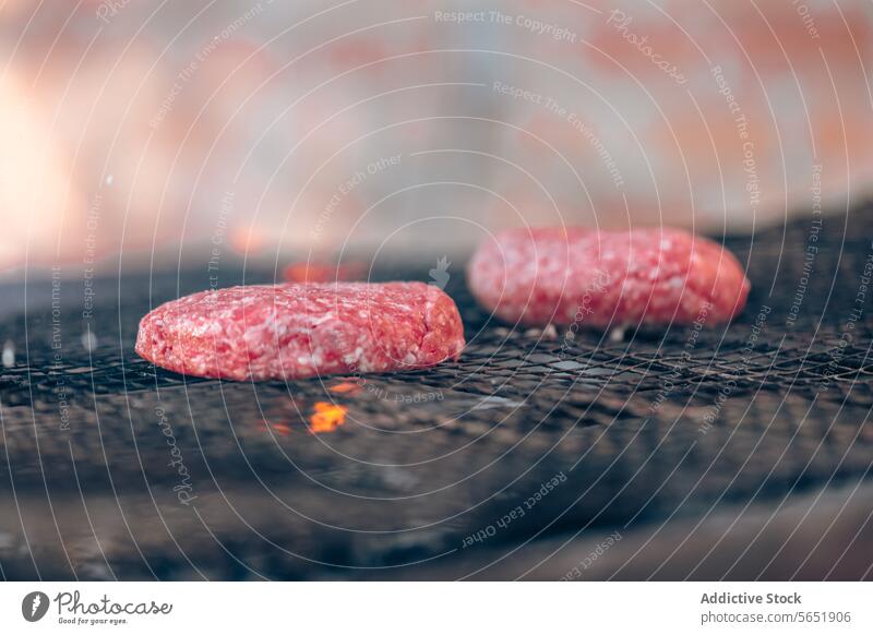 Rohe Burger-Patties beim Grillen über Holzkohleflammen Pastetchen roh Flamme Koch Barbecue Fleisch Grillrost Kohle glühend Essenz Hamburger Essen zubereiten