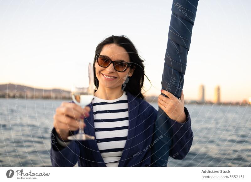 Junge Frau mit Glas Getränk am Meer stehend MEER Wasser Jacht Outfit Segelboot Ufer Tourismus idyllisch modern Boot aqua trinken Rippeln Küste übersichtlich