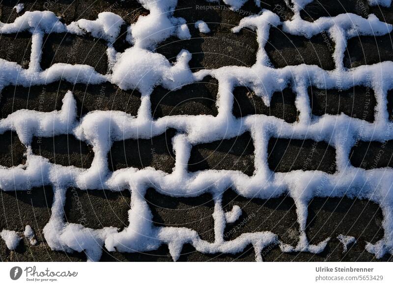 Graphisches Schneemuster in den Rillen von Pflastersteinen Winter Neuschnee graphisch Straße Gehweg kalt weiß Wetter Wege & Pfade Winterstimmung Spuren Kontrast