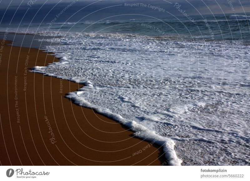 weiße Schaumkronen am dunklen Strand Meer Sturm Wellen Wasser Küste Gischt Urelemente Ferien & Urlaub & Reisen nass Sand Natur Brandung Wellengang Menschenleer