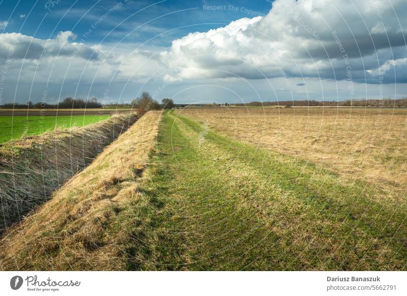 Entwässerungskanal neben einem unbefestigten Weg in einem Feld und bewölktem Himmel, Ostpolen Straße Schmutz ländlich Kanal Abfluss wolkig Klima leer trocknen