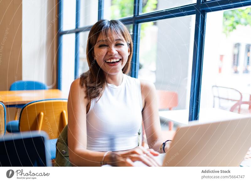 Fröhliche asiatische Frau bei der Arbeit in einem Café vor einem hellen Fenster in Chiang Mai, Thailand genießend abgelegen Sitzung Hintergrund heiter Glück