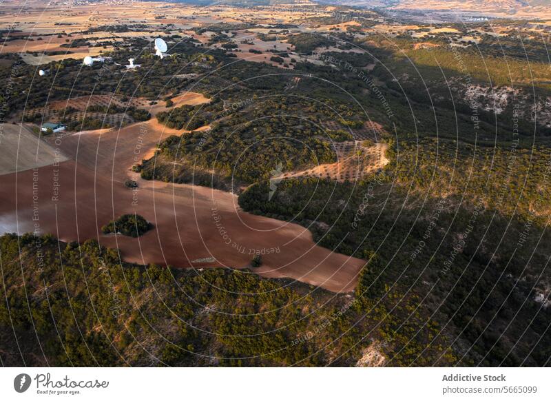 Das Abendlicht beleuchtet das Nebeneinander von fruchtbaren Feldern und dichten Wäldern in der Nähe der Satellitenschüsseln in Alcarria Antenne Guadalajara