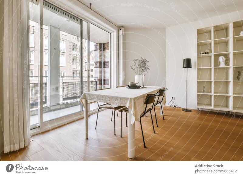 Helles und gemütliches Esszimmer mit Blick auf die Stadt Innenbereich Tisch Stühle Fenster Stadtansicht Bücherregal modern Appartement urban Gardine Stehleuchte