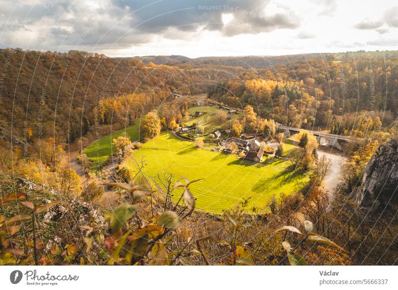 Felsige Umgebung in der Nähe der Stadt Dinant mit einem Wasserlauf, der natürliche Mäander in Herbstfarben bildet. Der Sonnenuntergang beleuchtet einen bunten Wald