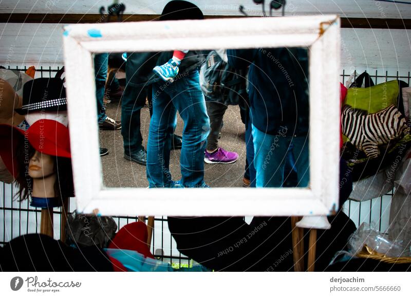 schaun wir mal was wird  / Eine kleine Menschenmenge steht auf dem Flohmarkt und stöbert in den gebrauchten  Klamotten. Ein hängender Spiegel erfasst das ganze.