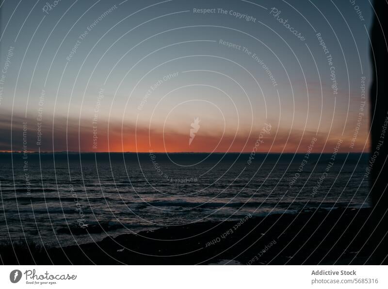 Blick auf einen Sonnenuntergang über dem Meer aus einem dunklen Raum, umrahmt von einem Fenster, das die Ruhe des Abends in Lariño, Galicien, einfängt Rahmen