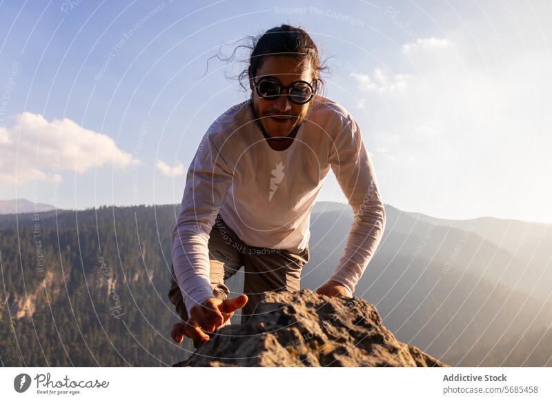 Mutiger junger Mann klettert auf einen Bergfelsen Aufstieg Berge u. Gebirge Kamm positiv Sonnenbrille Stil Klippe Stoff Natur Abenteuer Hochland reisen männlich