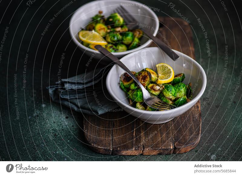 Von oben: Schüssel mit gegrilltem Rosenkohl, gewürzt mit Knoblauch und Gewürzen, garniert mit einer Zitronenscheibe, serviert auf einem Holzbrett mit einer Gabel