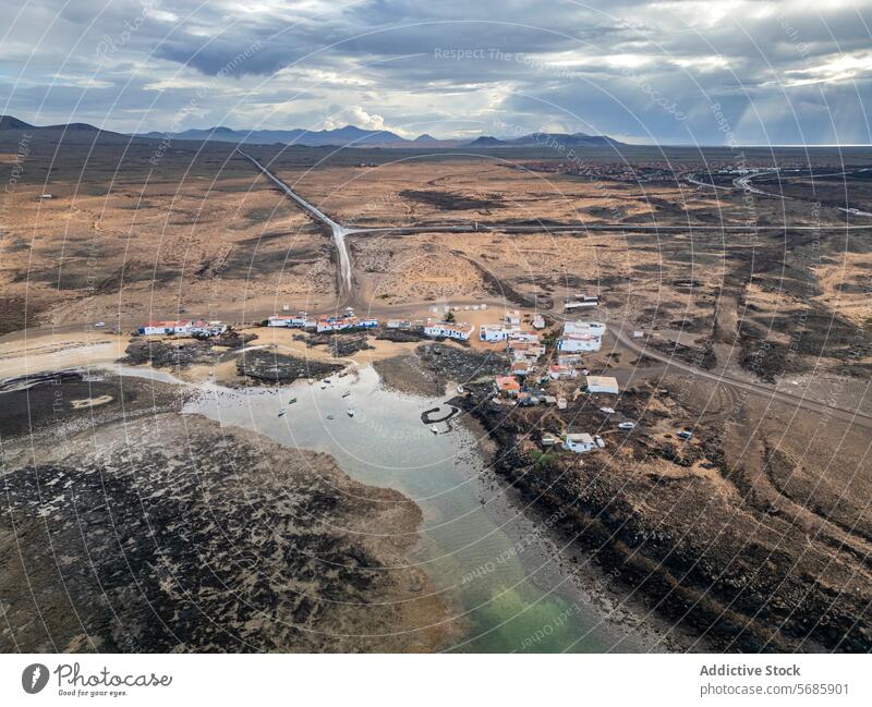 Luftaufnahme einer Küstensiedlung mit gewundenen Straßen an der trockenen Nordküste Fuerteventuras, von El Cotillo nach Majanicho, in der Nähe des Leuchtturms Faro del Toston