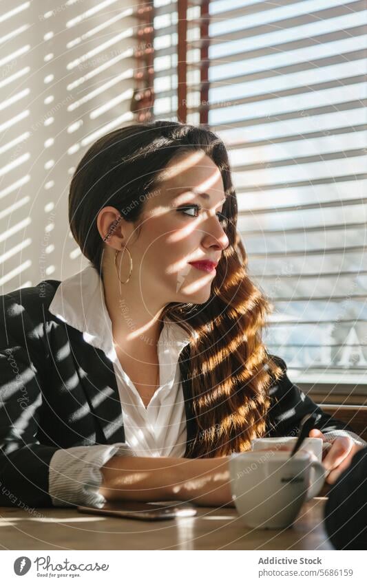 Kontemplative Frau genießt das Morgenlicht in Madrid Spanien Sonnenlicht beschaulich Gelassenheit nachdenklich Kaffee Tisch Smartphone sonnend Fenster Schatten