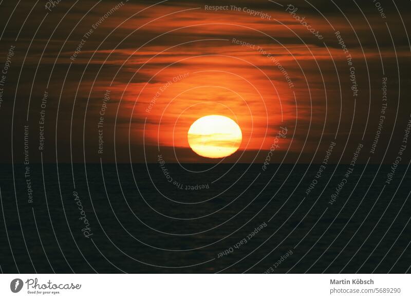 Sonnenuntergang über der Ostsee. Die rote Sonne versinkt im Meer. Abendstimmung Sonnenstrahlen Sonnenschein Reflexion & Spiegelung Küste winken reisen