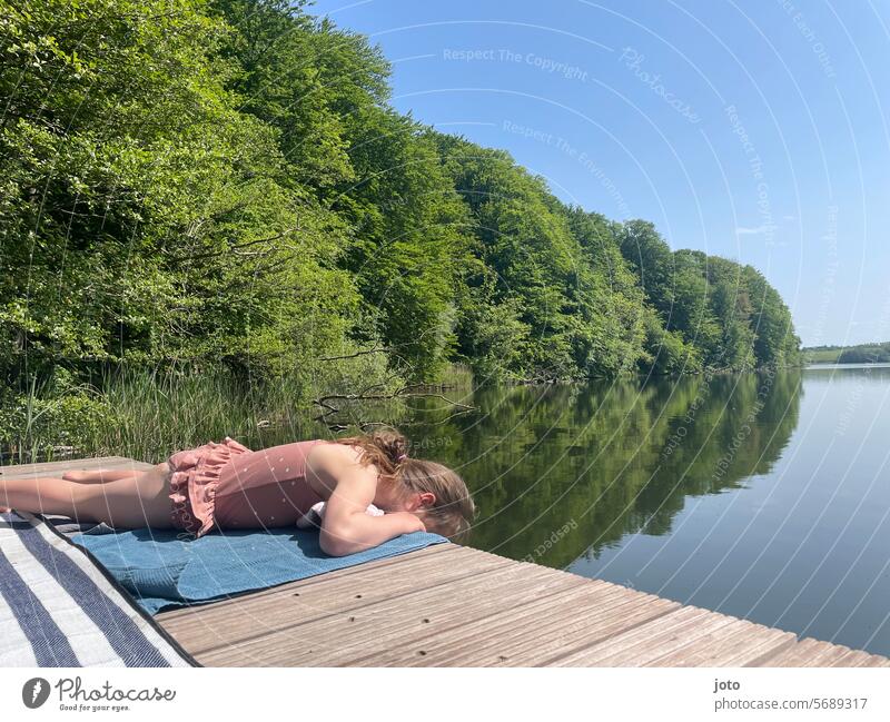 Mädchen liegt im Badeanzug auf einem Steg am See Sommer Sommerurlaub sommerlich Sommerferien Kind Kindheit Seeufer baden Badeurlaub Wasser badespaß Badesee