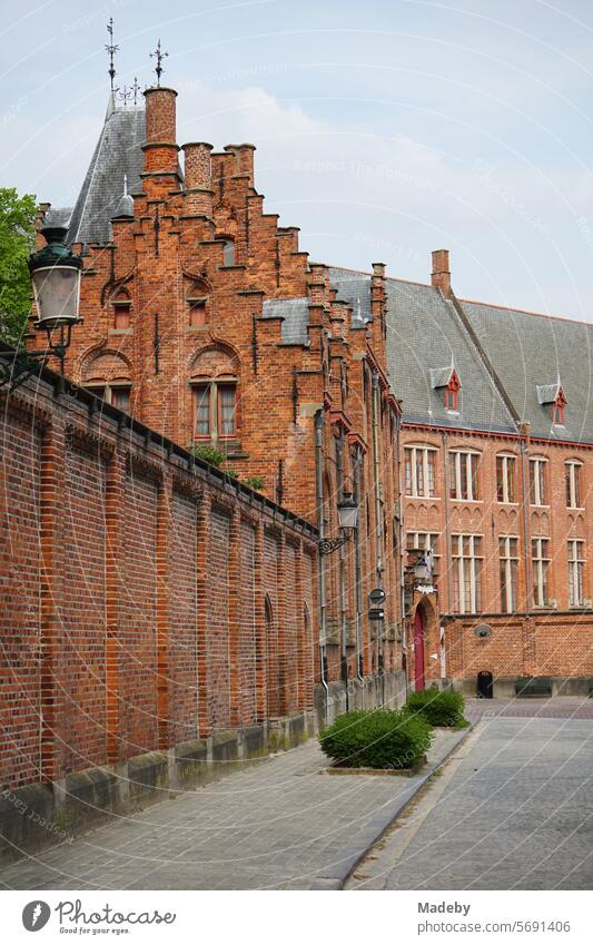 Alte Backsteinmauer in Rotbraun einer schönen alten Schule mit Treppengiebel in den Gassen der Altstadt von Brügge in Westflandern in Belgien dach gebäude