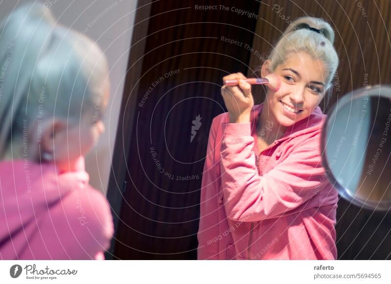 Blonde schöne Frau beim Schminken vor dem Spiegel blond Pferdeschwanz Bad jung Toilette Make-up Kosmetik anwendend Pulver Lächeln Aktion Bürste lockig Genuss