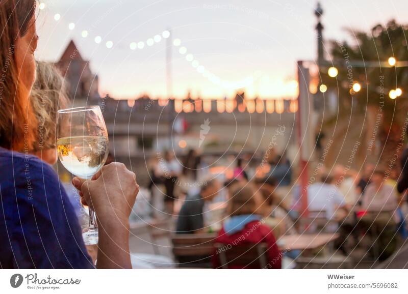 Eine Frau steht mit einem Getränk im Abendlicht und blickt über die festlich beleuchtete Anlage feiern tanzen Sommer Party Tanzfläche Lokal Biergarten warm