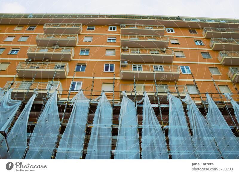 Wohnhaus mit Gerüst und Sicherheitsnetz, teilrenoviert. Baustelle wohngebäude Gerüstplane Fassade bauen Renovieren Haus Gebäude außen Baugerüst Abdeckung