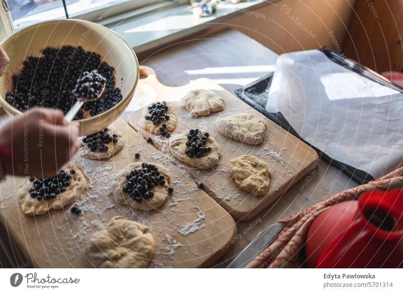 Frau bereitet zu Hause Heidelbeerbrötchen zu (Jagodzianka - traditionelles polnisches süßes Brötchen mit Heidelbeerfüllung) Blaubeeren Mehl Beerenfrucht Frucht