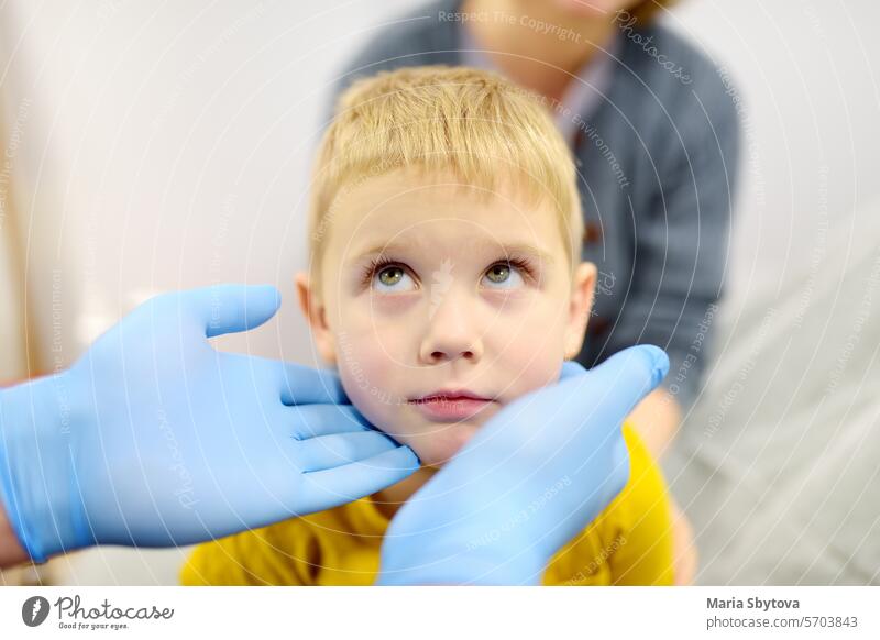 Ein niedlicher kleiner Junge und seine Mutter haben einen Termin bei einem Kinderarzt. Der HNO-Arzt untersucht die Lymphknoten eines kleinen Patienten.