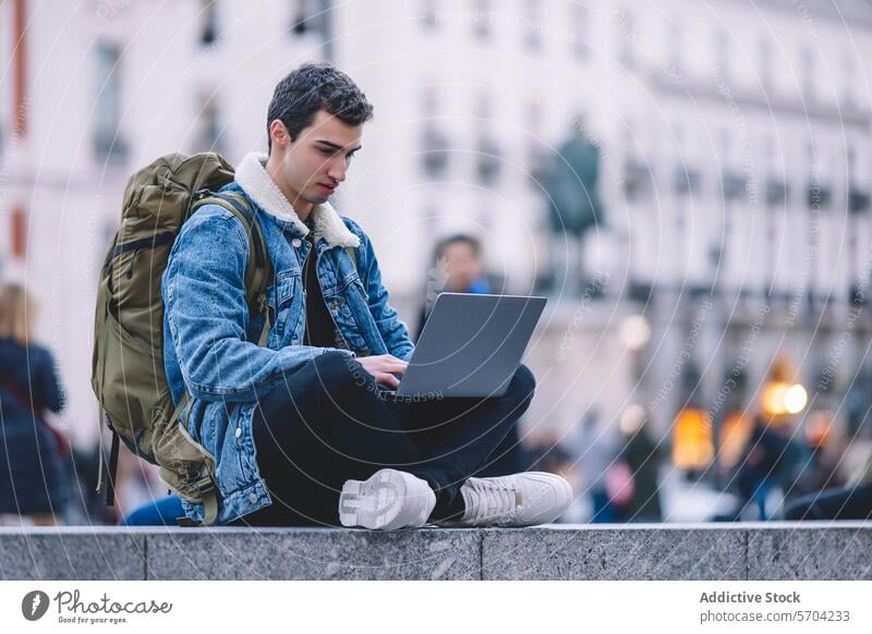 Junger Mann arbeitet an seinem Laptop, während er auf den Stufen eines belebten Madrider Platzes sitzt jung arbeiten Quadrat Freitreppe im Freien Stadtleben